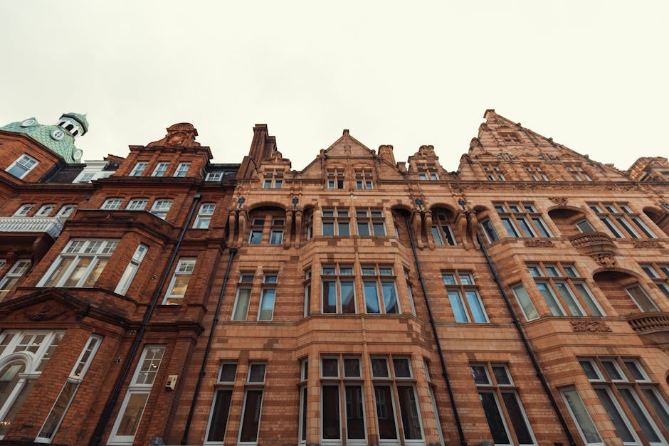 Photograph of an ornate, historic red-brick building in Knightsbridge, featuring intricate architectural details, tall multi-pane windows, and decorative stonework. The building's facade appears clean and well-maintained, with a clear view of its textured surfaces and traditional design elements. The sky above is overcast, casting soft, even lighting across the structure, highlighting its craftsmanship. This image exemplifies the type of properties that benefit from professional surface cleaning and deep cleaning services offered by Deep Cleaning Knightsbridge, ensuring hygiene and visual appeal for both residential and commercial spaces in the area.